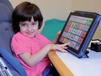 Kind mit Behinderung an einem Sprachcomputer